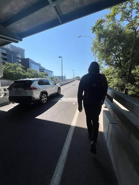 A silhouetted figure with a backpack walks along a sunlit road beneath an overpass, with a white Toyota RAV4 parked to the side. The image, paired with a message urging progress in finance through tokenization, serves as a visual metaphor for moving forward into the unknown despite uncertainty—much like a lone traveler venturing down a path that others may not yet understand.