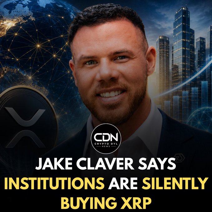 A thumbnail from Crypto DYL News featuring a smiling man in a suit set against a backdrop of city skyscrapers and a global network graphic with an XRP coin, titled "JAKE CLAVER SAYS INSTITUTIONS ARE SILENTLY BUYING XRP." The image visually supports the claim by pairing Jake Claver's portrait with symbols of institutional finance and global connectivity to emphasize the headline about quiet institutional accumulation of XRP.