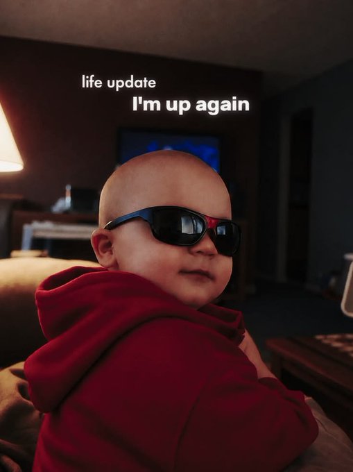 A bald baby wearing oversized black sunglasses and a red hoodie is captioned 'I'm up again' under 'life update'.
