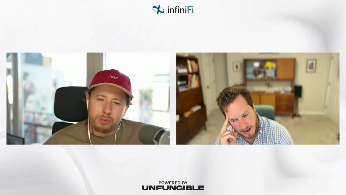 The image shows two men sitting next to each other, one wearing a red baseball cap and the other wearing a blue shirt with headphones around his neck. They are both looking at their phones or laptops, which suggests that they might be engaged in an online conversation or discussion related to the topic of AI replacing humans.