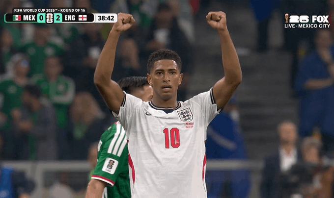 An England football player in a white jersey with the number 10 raises both arms in celebration during a FIFA World Cup 2026 Round of 16 match against Mexico, with the scoreboard showing MEX 0 - 2 ENG at 38:42, broadcast on FOX.