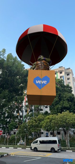 A large VeVe-branded box with a parachute and Teenage Mutant Ninja Turtle figure descending over a city street with a white van below.