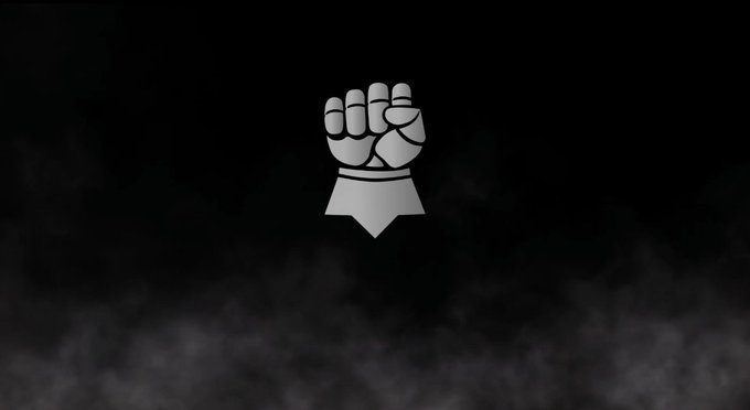 A stylized white fist logo on a dark, smoky background.