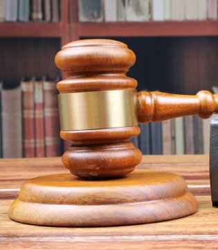 A wooden gavel rests on a matching base atop a desk, with bookshelves of legal volumes visible in the background. The gavel symbolizes the ongoing legal disputes over "Tung," suggesting that despite courtroom battles, ownership can be simplified by purchasing the token directly on Solana for $0.015.