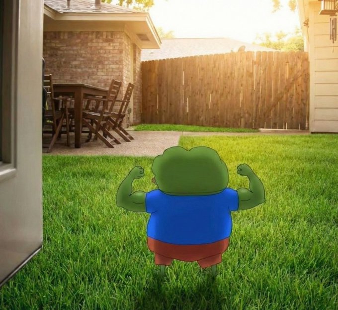 A cartoon frog character with a muscular human body, wearing a blue shirt and red shorts, flexes its arms while standing on a green lawn in a suburban backyard.