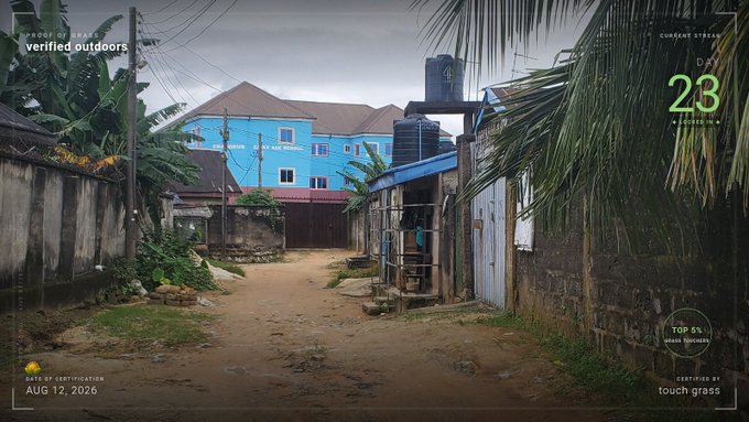 A view down a dirt road lined with houses and vegetation under an overcast sky, overlaid with a 'TOUCH GRASS' certification interface showing 'PROUD OF DARE: verified outdoors', 'DAY 23', and a 'DATE OF CERTIFICATION: AUG 12, 2026'.