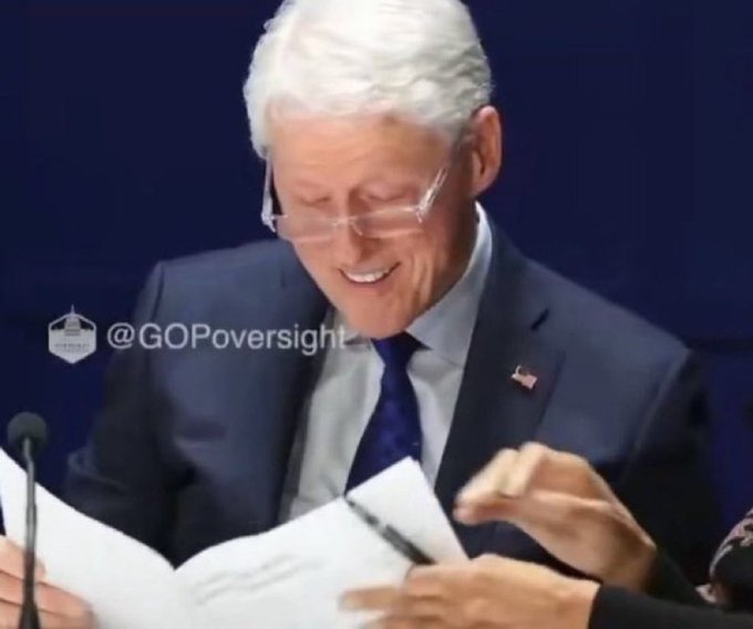 A man with white hair and glasses in a dark suit smiles as he holds documents, with the text "@GPOversight" displayed on the image. The image appears unrelated to the accompanying post listing top onchain traders, suggesting an ironic or satirical juxtaposition.
