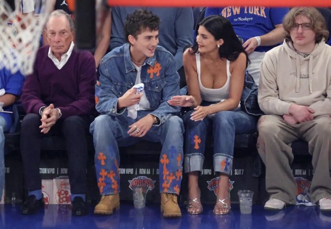 The image shows a group of people sitting together at a basketball game. There are four individuals visible - two men and two women. One man is wearing a blue denim jacket with orange crosses on it, while another man is wearing a purple sweater. The woman in the center has her arms crossed over her chest as she looks towards the camera. A sports ball can be seen in the background, indicating that they are attending a basketball game.

The post includes various stock market and financial terms such as "Bonds", " Nasdaq", "S&P 500", and "Bitcoin". These terms seem unrelated to the image of people sitting together at a basketball game but could potentially be related to the event or the individuals' personal interests, which may include investing in these markets.