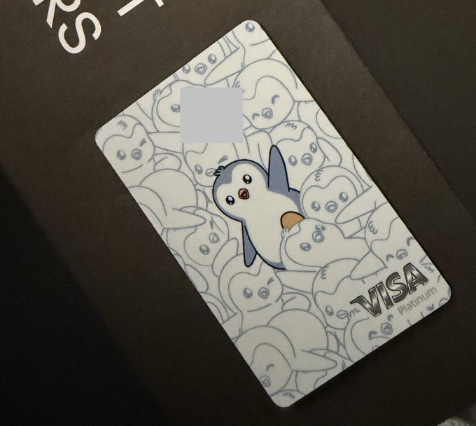 The image features a penguin-themed Visa card, which has been used for transactions. The card is placed on top of a black surface, possibly a table or countertop. The card itself is white with a blue border, and it displays the Visa logo in the center. The text "Just received my @KASTxyz crypto card that I use to spend my profits on Polymarket" suggests that the card has been used for online purchases related to cryptocurrency trading.
