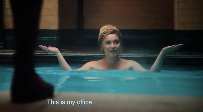 A woman is shown in a swimming pool with her arms raised in a shrugging gesture, with subtitle text reading 'This is my office.'