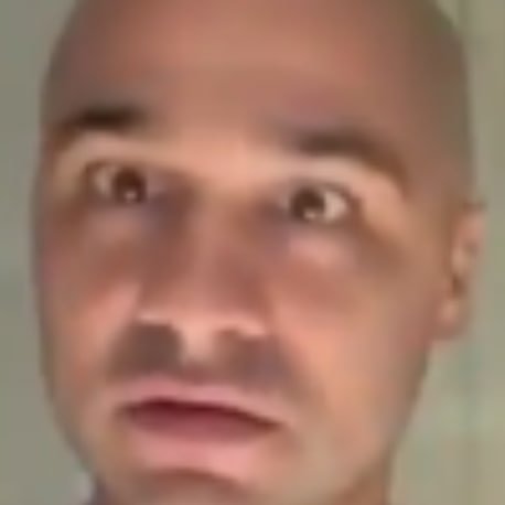 A blurry close-up of a man's face with a surprised or confused expression.