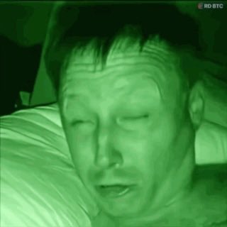 A night vision green-tinted image of a man with his eyes closed, with an 'MO BTC' watermark in the corner.