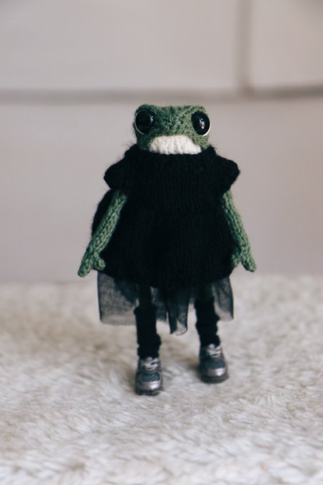 A small handmade knitted frog figurine dressed in a black sweater, tutu, and tiny sneakers sits on a fluffy white surface. The frog's dark, "goth" outfit humorously reflects the post's mood about dressing in funeral-like attire when facing Solana's declining chart.
