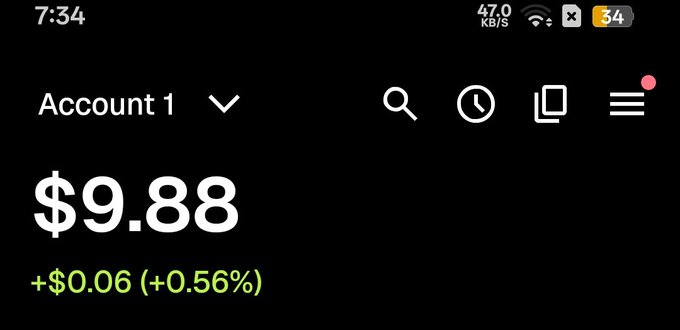 A mobile app screenshot showing 'Account 1' with a balance of $9.88, displaying a gain of +$0.06 (+0.56%) in green text on a black background, with a status bar showing 7:34 and 34% battery.