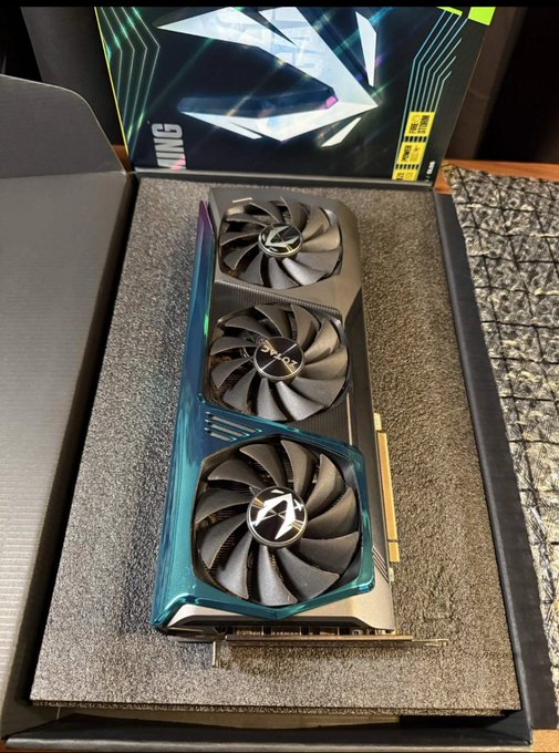 A new Aorus GeForce RTX 3090 graphics card sits unboxed in its packaging, ready to be added to a mining setup for $QUAI cryptocurrency. The image highlights the GPU hardware referenced in the post about expanding a mining arsenal for tensor commitment-based proof-of-work mining.