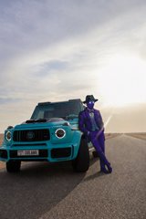 The image features a person wearing a purple suit, standing next to a blue car with a license plate that reads "SOLANA SUMMER". This suggests that the person might be attending or participating in an event related to the Solana Summer theme. The car is parked on a road, and the person appears to be posing for the photo while leaning against it.