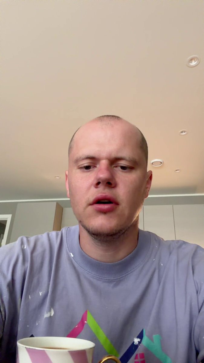 The image features a man wearing a purple shirt, sitting at a table with a cup of coffee in front of him. The background appears to be a kitchen or dining area, as there are cabinets visible behind the man. The caption on the image reads "Important day! $BTC $SPCX $HYPE $jap225 $us500 $NVDA". This suggests that it might be an important event or occasion for which the man is dressed up and enjoying a cup of coffee.