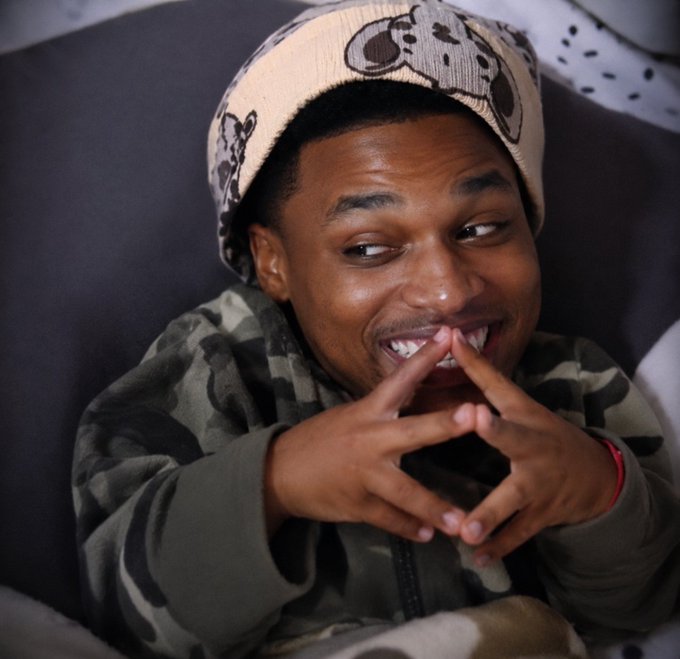 A young man wearing a cartoon-printed beanie and camouflage jacket smiles and makes a finger gun gesture toward the camera, his expression conveying amusement and disbelief. The image's playful, almost shocked demeanor visually complements the post's tone of astonishment at $ANSEM's record-breaking $7 million token airdrop, seemingly mocking or reacting to crypto figures like $MEGA, $QUID, and $DIME being outperformed.