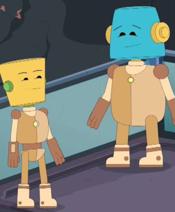 Two animated robot characters standing side by side in a dimly lit area, one smaller with a yellow cylindrical head and the other taller with a blue bucket-like head, both wearing tan uniforms with green circular chest emblems and brown gloves.