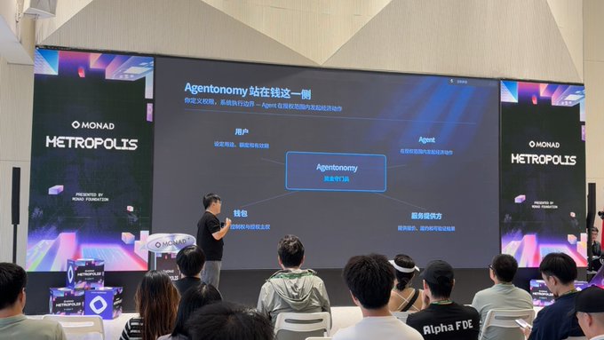 A presentation at the Monad Metropolis event, where a speaker stands before a large screen displaying a slide titled 'Agentonomy' with Chinese text explaining the concept, while an audience watches.