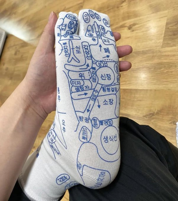A person holds up a white sock with a blue printed map design showing Korean text and various locations.