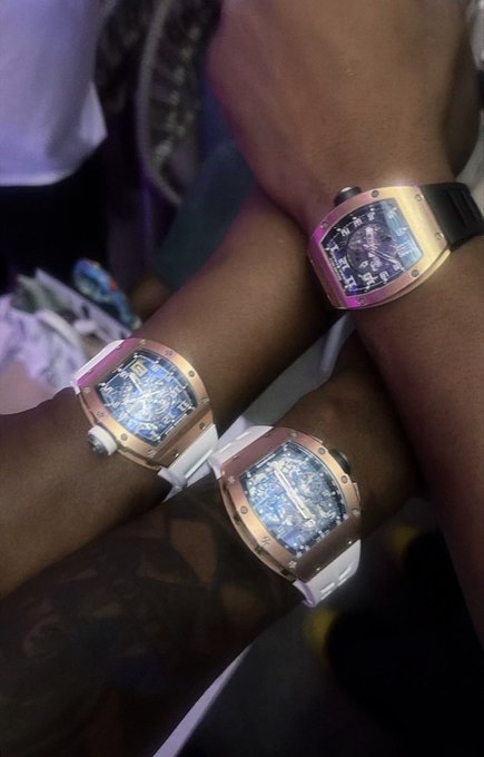 Three people showing off their wrists adorned with matching tonneau-shaped luxury watches featuring rose gold/pink cases, dark blue dials, and white straps.