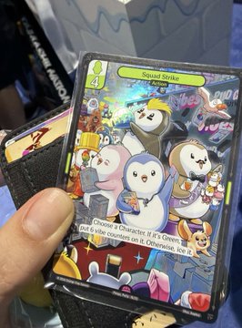 Close-up of a Pokémon trading card featuring 'Spooky Sticker' artwork with multiple ghost-type characters, held in a hand against what appears to be a convention background.