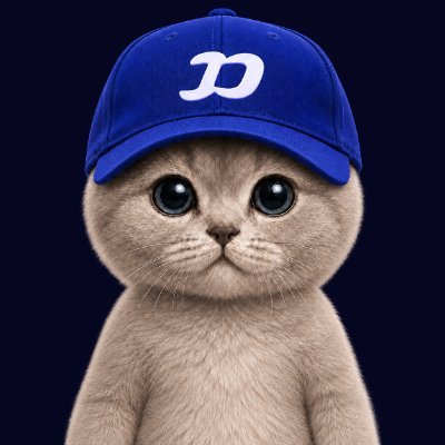 Digital image of a fluffy gray kitten with large eyes wearing a blue baseball cap with a white cursive 'D' logo.