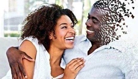 A joyful couple sitting close together on a couch, the man with a glitching/dissolving face effect, while the woman laughs with her head tilted back.