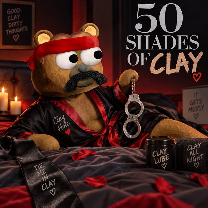 A stuffed teddy bear with a mustache and red blindfold lounges on a bed in a satin robe, holding handcuffs next to "Clay Lube" and "Clay All Night" pillows, with the title "50 SHADES OF CLAY" displayed prominently—matching the playful movie parody announcement by @ClayStonKz.