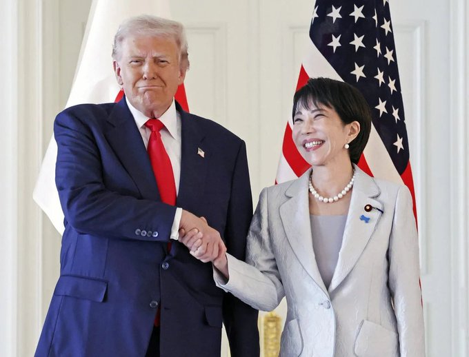 Two officials shake hands in front of American and Japanese flags at a formal diplomatic meeting. The image is used alongside a post claiming Japan announced plans to put its entire stock market on-chain and race the US to adopt #Bitcoin and crypto, lending a visual of high-level US-Japan diplomatic relations to the bullish crypto claim.