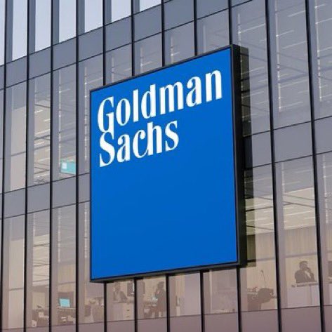 The blue Goldman Sachs logo sign mounted on the exterior glass facade of their office building.