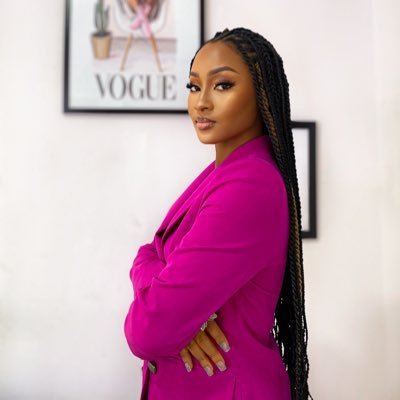 A woman in a vibrant magenta blazer poses confidently with her arms crossed, featuring long braided hair and manicured nails, with a framed "VOGUE" magazine cover visible on the wall behind her. The polished, stylish portrait aligns with the post's celebratory tone about connecting with a fellow crypto educator nominee.