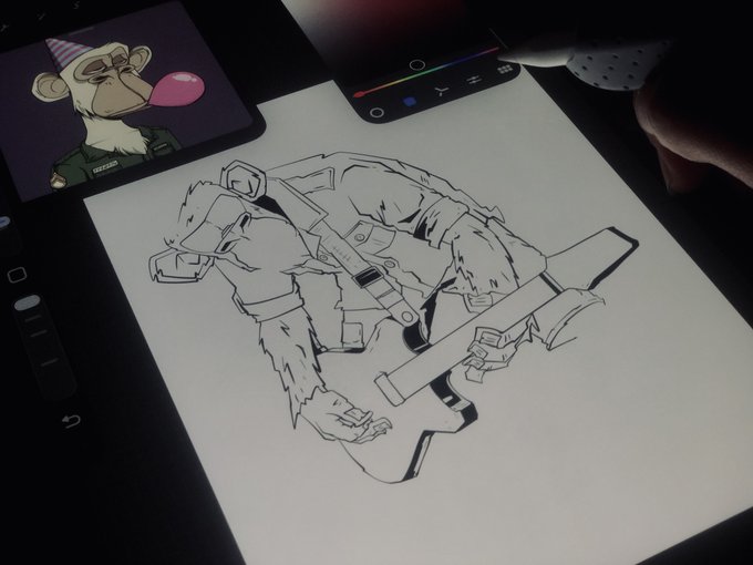 An overhead view shows a tablet displaying a digital drawing of a character in tactical gear, with a stylus held by a hand working on the illustration; a small window shows a cartoon mouse blowing a bubblegum bubble.