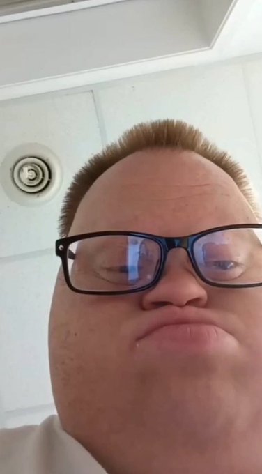 A man with glasses takes a low-angle selfie from inside what appears to be a bathroom or vented room, his expression blank and exaggerated, fitting the tongue-in-cheek request to be paid to delete a FOMO-related account.

No visible text, numbers, tickers, or names appear in the image.