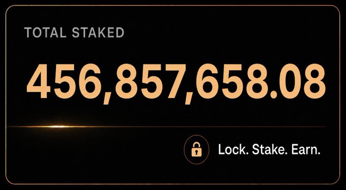 A dark interface panel displaying 'TOTAL STAKED 456,857,658.08' with a lock icon and the tagline 'Lock. Stake. Earn.' in glowing gold text.
