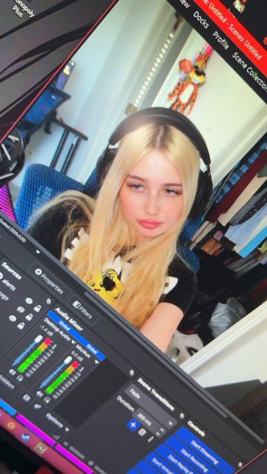 A blonde woman with headphones sits in front of a computer screen displaying OBS Studio's audio mixer with "Audio Mixer" and "Scene Transitions" visible, alongside "Twitch.tv/ibixie" in the corner, indicating she is a streamer preparing for a live broadcast.