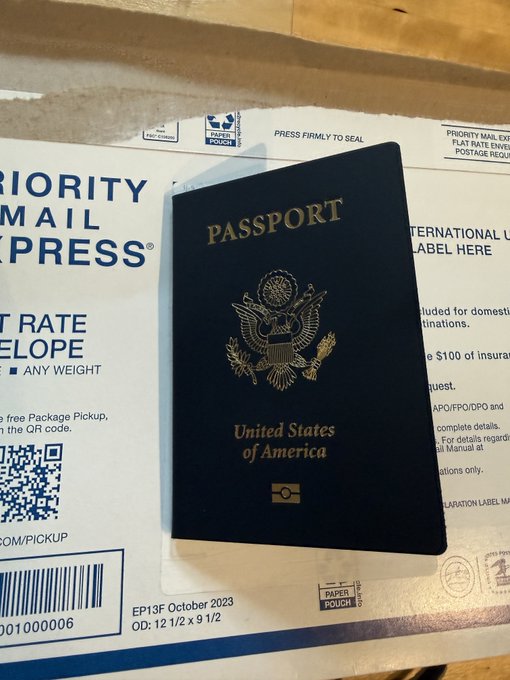 A US passport rests on top of a USPS Priority Mail Express envelope, showing tracking text "EP13F October 2023" and "OD: 12 1/2 x 9 1/2," illustrating the federal government's surprisingly quick processing and shipping turnaround time referenced in the post.