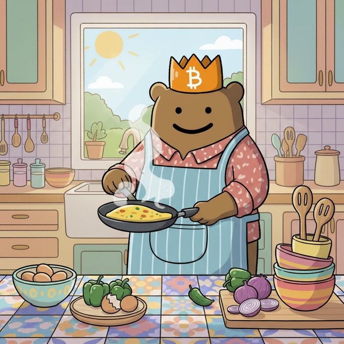 A cartoon illustration of a brown bear wearing a yellow Bitcoin (₿) crown and a blue apron, cooking eggs in a frying pan in a colorful kitchen with vegetables and bowls on the counter.