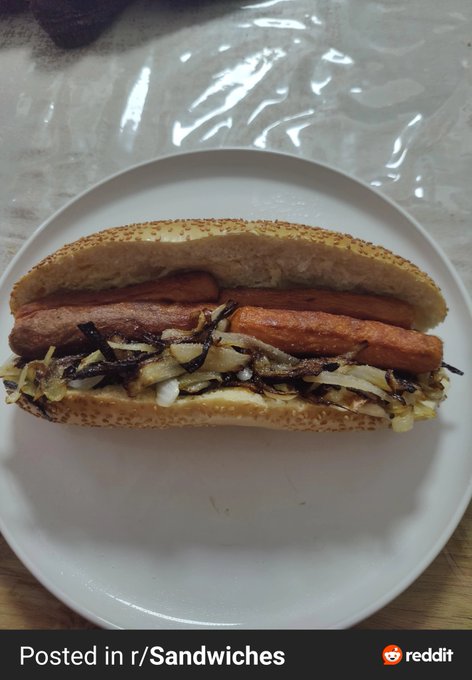 A hot dog topped with caramelized onions sits on a white plate over a wooden surface, with text reading "Posted in r/Sandwiches" alongside the Reddit logo. The image visually reflects the post's advice to take a break from stressful market charts and chill out with simple comfort food instead.