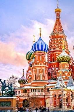 St. Basil's Cathedral in Moscow's Red Square stands majestically beneath a sunset sky, its iconic colorful onion domes and ornate spires dominating the frame. The image visually anchors the post about Moscow Exchange (MOEX) launching Bitcoin perpetual futures, symbolizing Russia's entry into cryptocurrency derivatives trading limited to qualified investors.