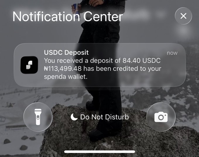 A smartphone Notification Center displays a USDC Deposit alert confirming that 84.40 USDC, totaling ₦113,499.48, has been credited to a spenda wallet, demonstrating a successful deposit that can be converted to naira as suggested in the caption.