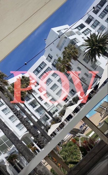 A tilted photograph of a white multi-story building with palm trees in front, featuring large pink text 'FDT' overlaid on the image.