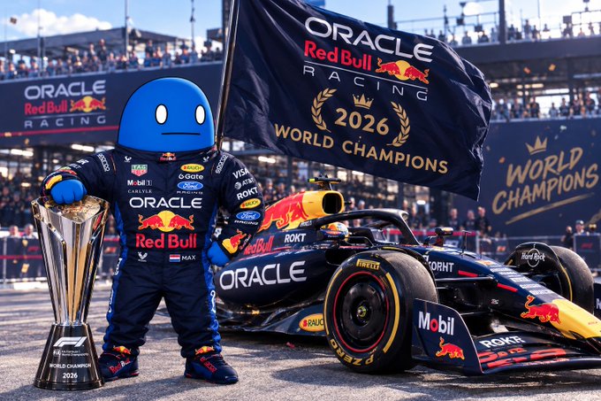 A racing scene featuring Oracle Red Bull Racing with a driver in racing suit and trophy beside an F1 car, holding a '2026 WORLD CHAMPIONS' flag in a stadium setting.