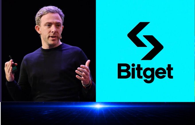 A man speaks on stage next to a bright cyan panel displaying the 'Bitget' cryptocurrency exchange logo.