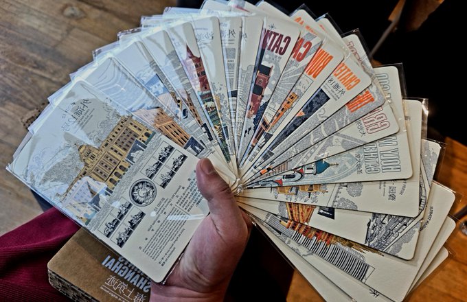 A hand fans out a collection of baseball trading cards in plastic sleeves, displaying various player cards with visible text like "TANAKA" and "MOST GAMES".