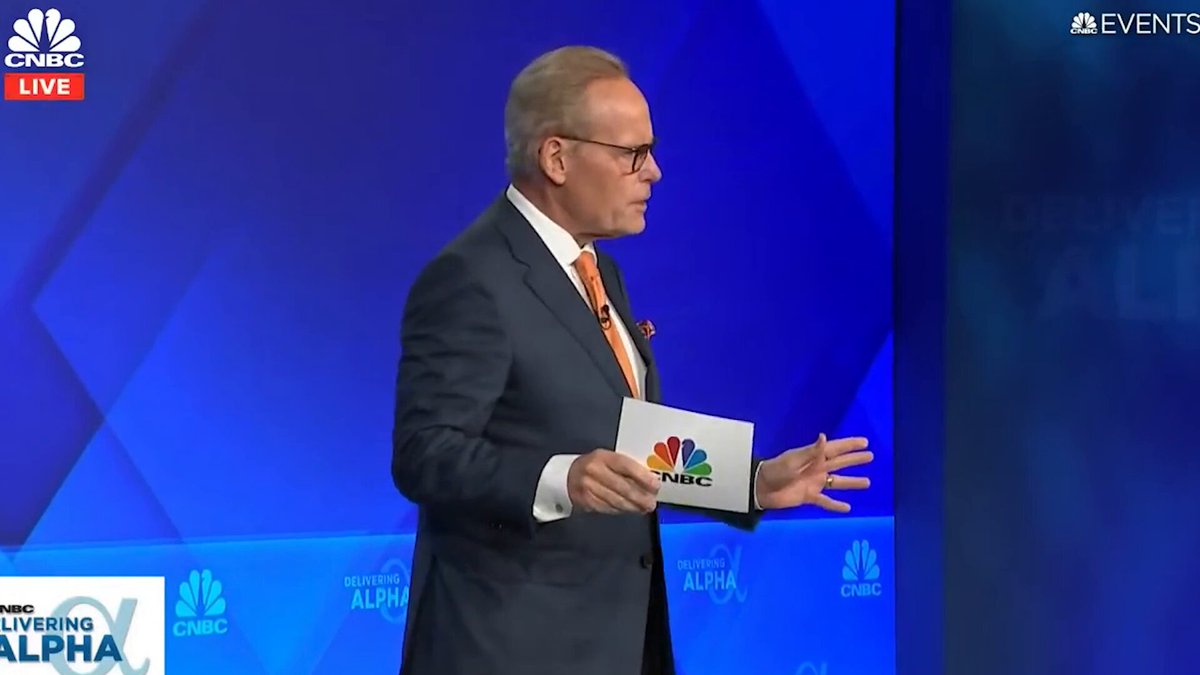 The image shows a man standing at a podium and holding up a piece of paper with the words "PBS" written on it. He appears to be giving an interview or speaking about something related to the "PBS". There are other elements in the image, such as logos from other TV networks (e.g., ABC) and text indicating that this is part of a segmented show called "My All-In interview". The content suggests that it could be discussing or reviewing a particular topic for the network, possibly something related to programming or media coverage.