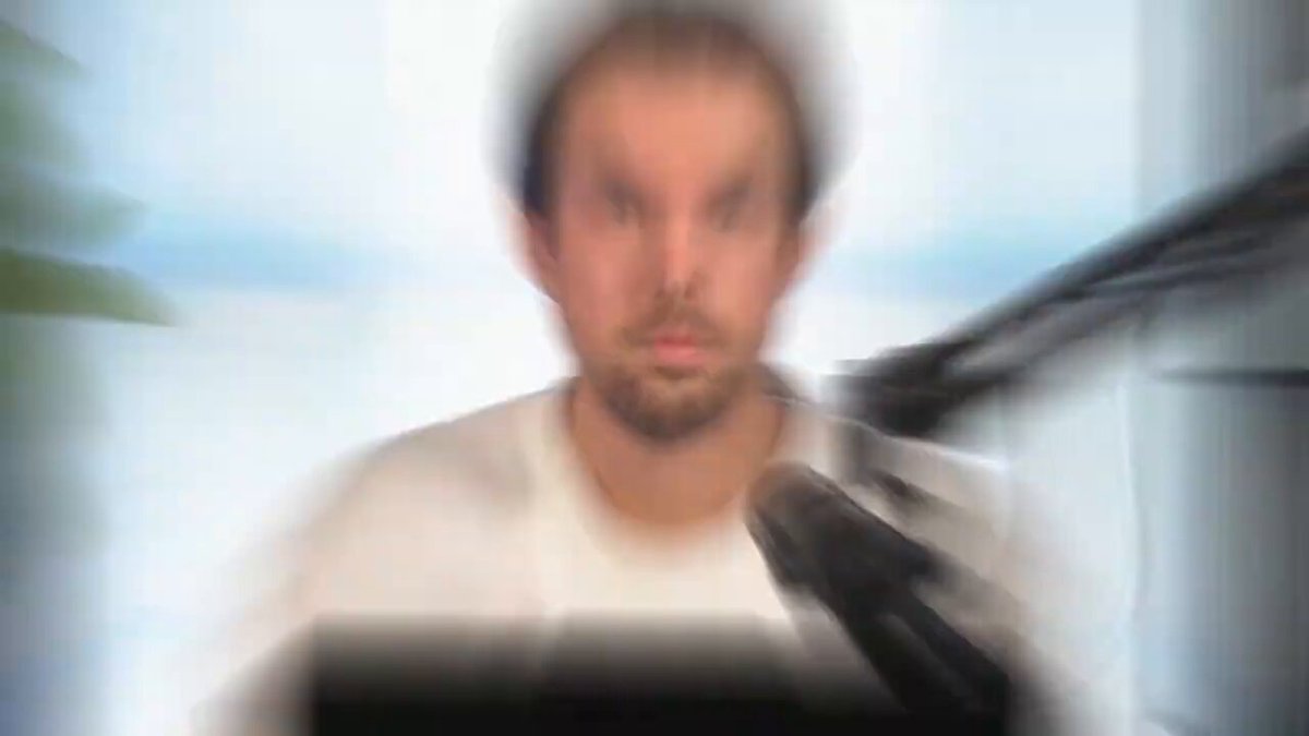In the image, a man wearing a white shirt sits at a desk with a computer monitor next to him. He appears focused or perhaps engrossed in something on his computer screen. The background of the photo seems blurry, drawing attention to the main subject - the man. There is no specific information about Bitcoin hitting $61K in the image.