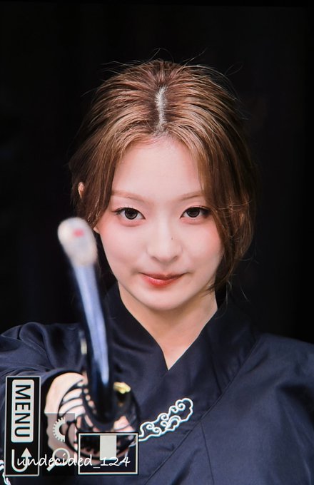 A young woman with brown hair in an updo holds a sword in front of her face while wearing a black traditional garment, with 'MENU' and 'undefined_1_4' text overlay.