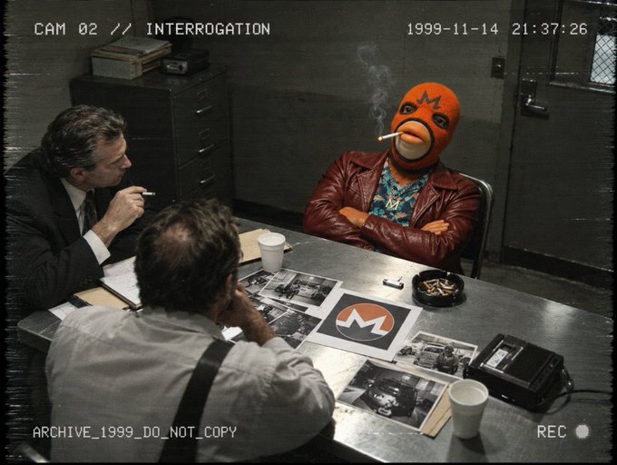 An archival photograph from 'CAM 02 // INTERROGATION' dated '1999-11-14 21:37:26' showing detectives interrogating a figure wearing an orange wrestling mask and brown coat.